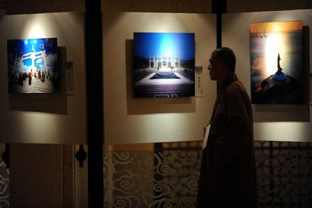 A visitor walks past photographs during a photo exhibiton on Buddhism during the Second World Buddhist Forum (WBF) in Wuxi, east China's Jiangsu Province, on March 29, 2009. 