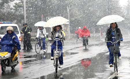 Students ride bicycle against snow on a street in Rushan City, east China's Shandong Province, March 30, 2009. A sleet hit the city on Monday, with precipitation at 4.7 millimeters by 8 a.m. on Monday.