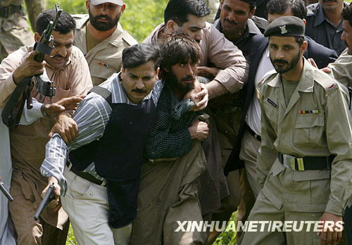 Police officials detain a suspected militant from the site of a shooting at a police training centre in Lahore on March 30, 2009.