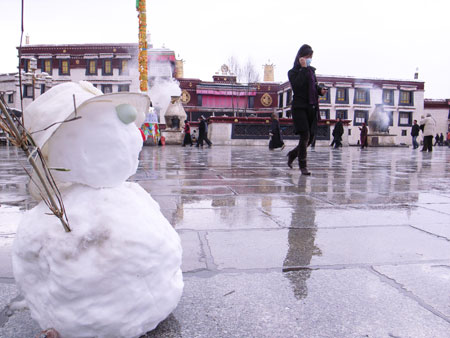 A woman walks past a snowman on the square of the Jokhang Temple in Lhasa, southwest China's Tibet Autonomous Region, after a snowfall on March 30, 2009. 