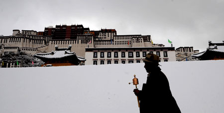 A man of Tibetan ethnic group walks on the snow-covered square in Lhasa, southwest China's Tibet Autonomous Region, on March 30, 2009. 