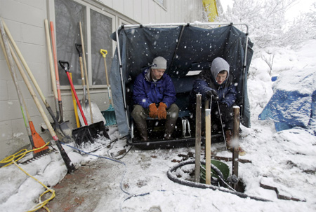 Steve Schaefer (L) and Jim Cella sit in a portable fish house as they tend to one of many pumps inside a sandbag dike that protects Schaefer's home from the flooding Red River in Moorhead, Minnesota, March 30, 2009. 