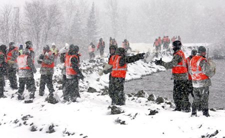 U.S. Army National Guard soldiers spread sandbags along a dike as they prepare to launch a large sheets of plastic with sandbag weights over the side of an earthen dike on the southside of Fargo, North Dakota March 30, 2009. 