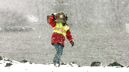 A U.S. Army Corps. of Engineers employee carries a box with a plastic sheet on a dike on the southside of Fargo, North Dakota as snow begins to fall March 30, 2009. Engineers hope a plastic barrier will help prevent erosion to the dike as snow followed by high winds and blizzard conditions enter the region. 