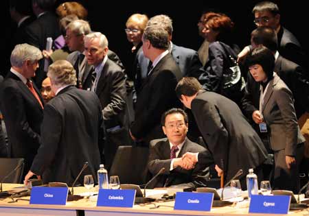 Chinese Vice Foreign Minister Wu Dawei (C, Seated) shakes hands with a Colombian representative during a high-level conference in Hague, the Netherlands, on March 31, 2009.