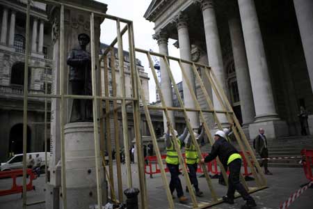 Workers place battens around a war memorial statue outside the building of the Royal Exchange in London March 31, 2009. The British capital is bracing for protests before and during the summit of the Group of 20 Countries, to be held on April 2. 