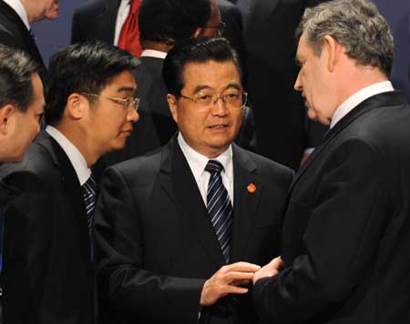 Chinese President Hu Jintao (2nd R) talks with British Prime Minister Gorden Brown (R) as they prepare to pose for a family photo during the Group of 20 summit in London, Britain, April 2, 2009. [Xinhua] 