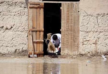 An Afghan pulls out the water from his house after a heavy rain in Kabul, Afghanistan, April 2, 2009. Heavy rainfall over the past 24 hours in Afghan capital Kabul claimed the life of one young man and destroyed or damaged some mud houses on Thursday. 