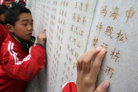 Visually disabled Chinese children touch names of deceased heroes engraved on a monument at a local cemetery for revolutionary martyrs in Xuchang city, central China's Henan province, April 2, 2009, two days prior to the Qingming festival, or the tomb sweeping day, that falls on April 4.