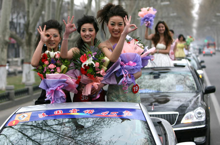 Models pose for photos on the car during the motorcade tour around Luoyang, central China's Henan Province, April 2, 2009. A motorcade consisting of luxury cars toured around Luoyang city on Thursday to greet the eighth luxury car show opened on April 3. (Xinhua/Li Shubao) 