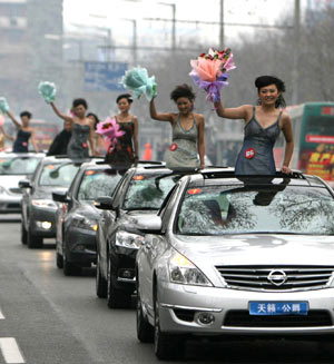 Models pose for photos on the cars during the motorcade tour around Luoyang, central China's Henan Province, April 2, 2009. A motorcade consisting of luxury cars toured around Luoyang city on Thursday to greet the eighth luxury car show opened on April 3. (Xinhua/Li Shubao)