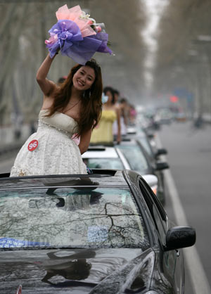 Models pose for photos on the cars during the motorcade tour around Luoyang, central China's Henan Province, April 2, 2009. A motorcade consisting of luxury cars toured around Luoyang city on Thursday to greet the eighth luxury car show opened on April 3. (Xinhua/Li Shubao) 