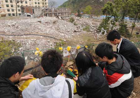 Li Yang (R1), a student from Beichuan Middle School and also a survivor from the devastating earthquake striking southwest China's Sichuan Province May 12, 2008, mourns the earthquake victims at the ruins of Beichuan Middle School in Beichuan County, southwest China's Sichuan Province, April 4, 2009.