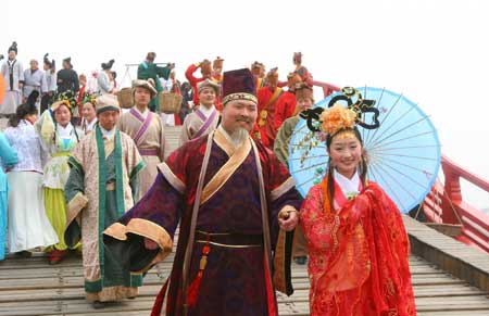 Chinese people in trational costumes walk along a bridge to showcase the life of China's Northern Song Dynasty (960-1126 A.D.) at a tourism promotional initiative during the Qingming festival, or the Tomb-sweeping Day, in Kaifeng city, central China's Henan Province, April 4, 2009.