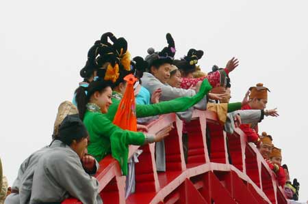 Chinese people in trational costumes gesture on a bridge to showcase the life of China's Northern Song Dynasty (960-1126 A.D.) at a tourism promotional initiative during the Qingming festival, or the Tomb-sweeping Day, in Kaifeng city, central China's Henan Province, April 4, 2009.[Xinhua]