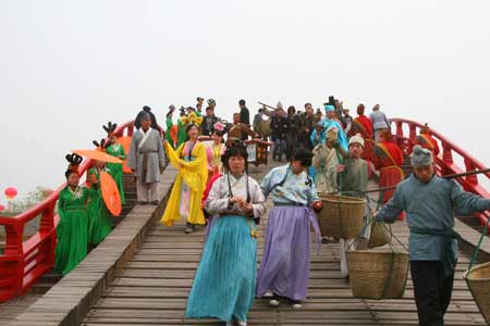 Chinese people in traditional costumes walk along a bridge to showcase the life of China's Northern Song Dynasty (960-1126 A.D.) at a tourism promotional initiative during the Qingming festival, or the Tomb-sweeping Day, in Kaifeng city, central China's Henan Province, April 4, 2009. 