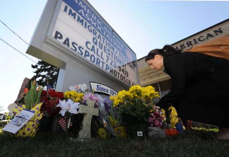 A woman offers flowers to mourn for victims killed in Friday's shooting rampage at the American Civic Association in Binghamton, the United States, on April 5, 2009. A total of 14 people of eight different countries of origin were killed in Friday's deadly shooting rampage in downtown Binghamton. [Xinhua]