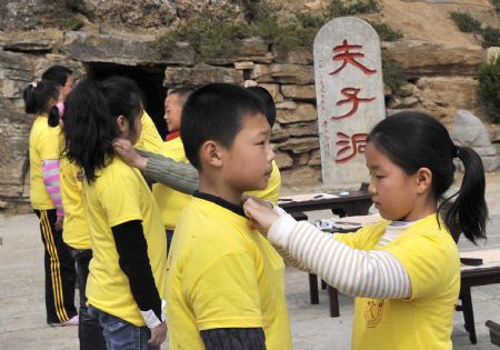 Kids tide themselves up before taking part in the ceremony to commemorate Confucius, at the Confucian temple in Qufu, east China's Shandong Province, April 4, 2009. [Xinhua]