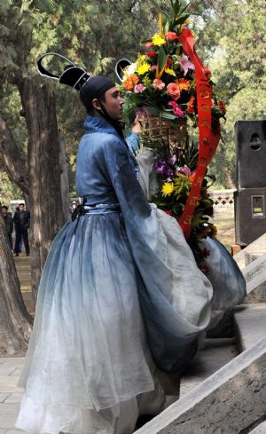  College students in ancient costumes offer flowers in the ceremony to commemorate Confucius, at the Confucian temple in Qufu, east China's Shandong Province, April 4, 2009. [Xinhua]