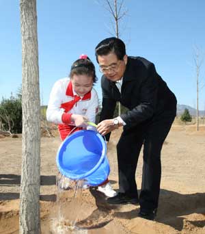 Chinese President Hu Jintao (R) waters a newly planted maidenhair tree with a young pioneer in Beijing, April 5, 2009. [Xinhua]