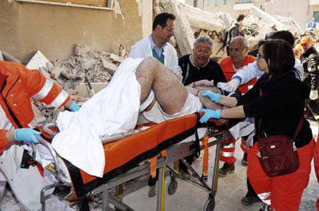 Rescue workers carry an injured man away from his house in Aquila April 6, 2009. A powerful earthquake struck a huge swathe of central Italy as residents slept on Monday morning, killing at least 100 people when houses, churches and other buildings collapsed. 