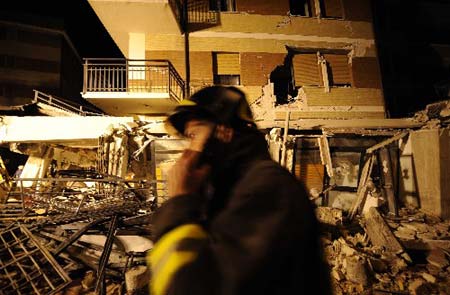 A rescuer walks past a collapsed building in L'aquila, Italy, earth April 7, 2009. The strong earthquake that hit central Italy on Monday has killed at least 150 people, injured some 1,500 and left around 70,000 homeless, Italian media reported on Tuesday.(Xinhua/Wu Wei) 