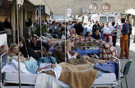 People rest outdoors after an earthquake caused the collapse of St. Salvatore Hospital in Aquila April 6, 2009. A powerful earthquake struck a swathe of central Italy as residents slept on Monday morning, killing more than 150 people and flattening whole towns.