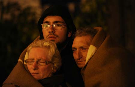 Three people cover themselves with a blanket as they take a rest in L'aquila, Italy, early April 7, 2009. The strong earthquake that hit central Italy on Monday has killed at least 150 people, injured some 1,500 and left around 70,000 homeless, Italian media reported on Tuesday. (Xinhua/Wu Wei) 