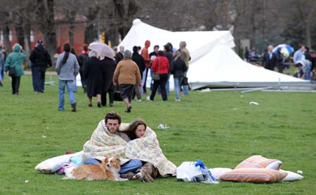 A couple keep warm as they rest sit at a tent camp in Aquila April 6, 2009. A powerful earthquake struck a huge swathe of central Italy as residents slept on Monday morning, killing at least 150 people when houses, churches and other buildings collapsed, officials said.