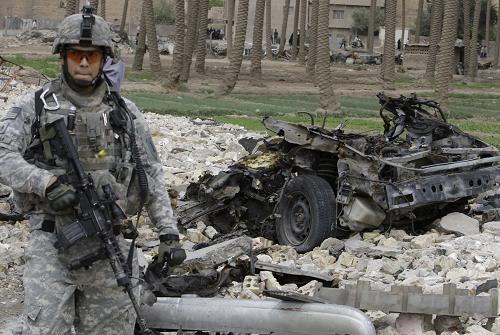 A U.S. soldier stands guard near the wreckage of a vehicle used in a car bomb attack in Baghdad April 7, 2009. A car bomb killed nine people and wounded 18 in the Shi'ite Kadhimiya district of northwest Baghdad on Tuesday, police said, a day after seven car bombs killed 37 people across the Iraqi capital.