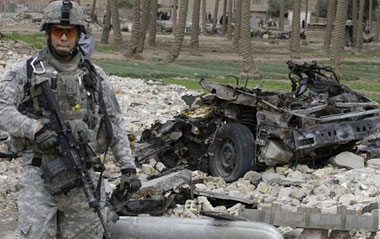 A U.S. soldier stands guard near the wreckage of a vehicle used in a car bomb attack in Baghdad April 7, 2009. A car bomb killed nine people and wounded 18 in the Shi'ite Kadhimiya district of northwest Baghdad on Tuesday, police said, a day after seven car bombs killed 37 people across the Iraqi capital.