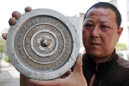  A Chinese archaeologist showcases a bronze mirror with inscriptions at the excavation site of an ancient tomb possibly dated to the early stage of 8 A.D.-220 A.D. at Jiaozuo city in central China's Henan province April 7, 2009. The archaeologists have unearthed some 200 pieces of cultural relics since the end of March 2009, including bronze mirrors, iron swords, gallipots and pottery dressing cases. (Xinhua/Yang Fan) 