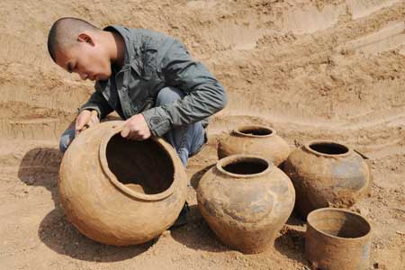A Chinese archaeologist clears pottery pots at the excavation site of an ancient tomb possibly dated to the early stage of 8 A.D.-220 A.D. at Jiaozuo city in central China's Henan province April 7, 2009. 