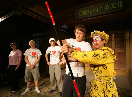 A British middle school student learns how to play the 'Jingubang', a stage property, from an actor of Kunqu Opera in Suzhou city of east China's Jiangsu Province, April 8, 2009. Over thirty British middle school students visited China Kunqu Opera Museum in Suzhou on Wednesday and learned impromptu some skills of Kunqu performance, when they were on cultural exchange visits to Suzhou Foreign Languages School. [Xu Zhiqiang/Xinhua] 