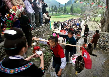 A procession of ethnic Miao women drink the threshold wine upon their entrance into the village, for a frolic celebration of the Guzang Festival, at the Yangfang Village, Taijiang County, southwest China's Guizhou Province, April 8, 2009. 