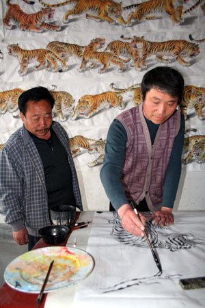 Wang Demin, a farmer fond of painting, paints a tiger before a fellow villager at home in Tancheng County of east China's Shandong Province, April 8, 2009. Wang started to paint tigers this January and has finished 68 pieces of tiger pictures as he planed to make a hundred pieces before China's National Day on this Oct. 1st. (Xinhua/Zhang Chunlei)