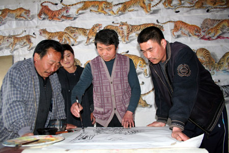 Wang Demin, a farmer fond of painting, paints a tiger before his fellow villagers at home in Tancheng County of east China's Shandong Province, April 8, 2009. Wang started to paint tigers this January and has finished 68 pieces of tiger pictures as he planed to make a hundred pieces before China's National Day on this Oct. 1st. (Xinhua/Zhang Chunlei)