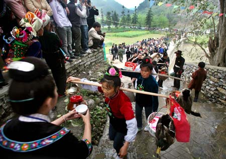 A procession of ethnic Miao women drink the threshold wine upon their entrance into the village, for a frolic celebration of the Guzang Festival, at the Yangfang Village, Taijiang County, southwest China's Guizhou Province, April 8, 2009.