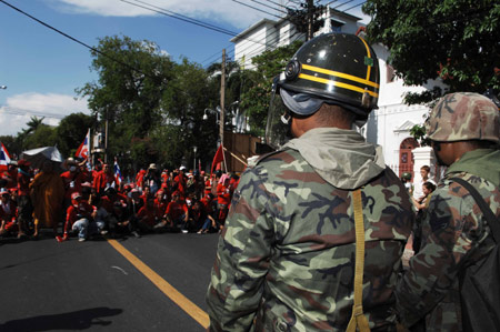 Thai soliders stand guard as anti-government protestors block a road in front of the Interior Ministry in Bangkok, capital of Thailand, on April 12, 2009. Red-shirted protestors forced into the Interior Ministry on Sunday, soon after Prime Minister Abhisit Vejjajiva declared a state of emergency in Bangkok and some districts in five nearby provinces. [Xinhua]