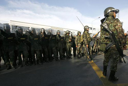 Soldiers stand guard as supporters of former Thai prime minister Thaksin Shinawatra block the main road during a state of emergency in Bangkok April 12, 2009. Troops fired into the air as Thai anti-government protesters stormed the country's interior ministry on Sunday after Prime Minister Abhisit Vejjajiva declared a state of emergency in the capital. [Xinhua/Reuters]