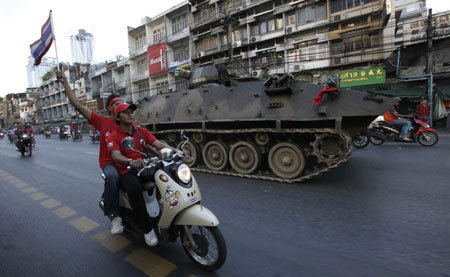 Supporters of ousted Thai prime minister Thaksin Shinawatra ride motorcycles beside an armoured personnel carrier returning to a military base in Bangkok April 12, 2009 a day after the ASEAN Summit was cancelled. [Xinhua/Reuters]