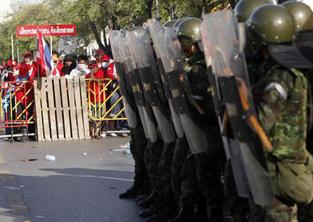 Soldiers stand guard as supporters of former Thai prime minister Thaksin Shinawatra block the main road during a state of emergency in Bangkok April 12, 2009. [Xinhua/Reuters]