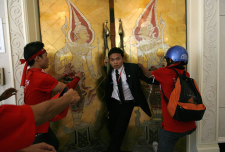 A summit staff tries to stop red-shirted supporters of ousted Thai prime minister Thaksin Shinawatra from entering one of the rooms inside a venue of the 14th ASEAN Summit and Related Summits in Pattaya April 11, 2009.[Xinhua/Reuters]