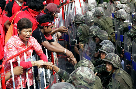 Supporters of ousted Thai prime minister Thaksin Shinawatra shake hands with soldiers blocking the road near the venue of the 14th ASEAN Summit and Related Summits in Pattaya April 11, 2009. [Xinhua/Reuters]