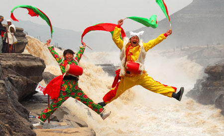 Two performers spring up during a highprofile tour-entertaining waist drum dance on the Hukou (Kettle Mouth) Waterfall on the Yellow River, in Yichuan, northwest China's Shaanxi Province, April 12, 2009. The scenery zone of Hukou Waterfall has been reopened to tourists as of April 1 after a moratorium on account of unprecedented ice floes jam on the Yellow River in early January.[Rao Erbao/Xinhua]