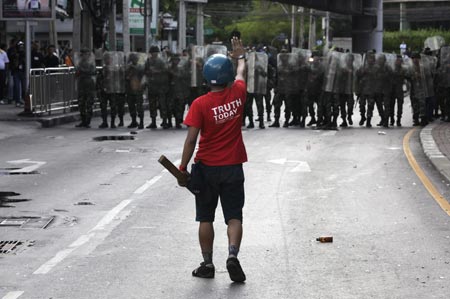 A supporter of ousted Thai Prime Minister Thaksin Shinawatra gestures to riot troops guarding a road in Bangkok April 13, 2009. The Thai army cracked down on anti-government protesters on Monday, firing warning shots in a major junction of the capital at activists who responded by hurling petrol bombs at them. ([Xinhua/Reuters]