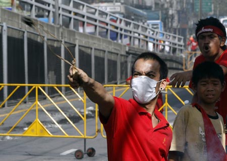 A supporter of ousted Thai prime minister Thaksin Shinawatra uses a slingshot during a protest in Bangkok April 13, 2009. The Thai army cracked down on anti-government protesters on Monday, firing warning shots at a major junction in the capital at demonstrators who responded by hurling petrol bombs. ([Xinhua/Reuters]