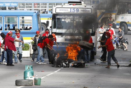 Supporters of ousted Thai prime minister Thaksin Shinawatra burn tyres as they block a main road in Bangkok April 13, 2009. The Thai army cracked down on anti-government protesters on Monday, firing warning shots at a major junction in the capital at demonstrators who responded by hurling petrol bombs. ([Xinhua/Reuters]