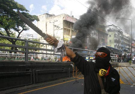 A supporter of ousted Thai prime minister Thaksin Shinawatra brandishes a weapon during a protest in Bangkok April 13, 2009. The Thai army cracked down on anti-government protesters on Monday, firing warning shots at a major junction in the capital at demonstrators who responded by hurling petrol bombs. ([Xinhua/Reuters]