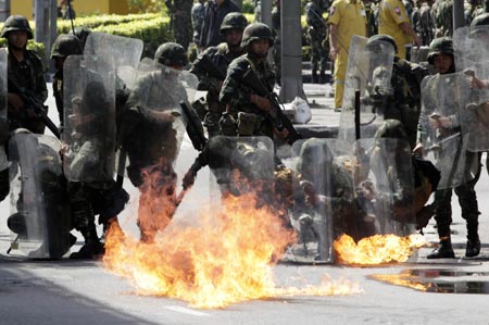 Riot troops take cover as a petrol bomb hurled by a supporter of ousted Thai Prime Minister Thaksin Shinawatra explodes in Bangkok April 13, 2009. The Thai army cracked down on anti-government protesters on Monday, firing warning shots at a major junction in the capital at demonstrators who responded by hurling petrol bombs. [Xinhua/Reuters]